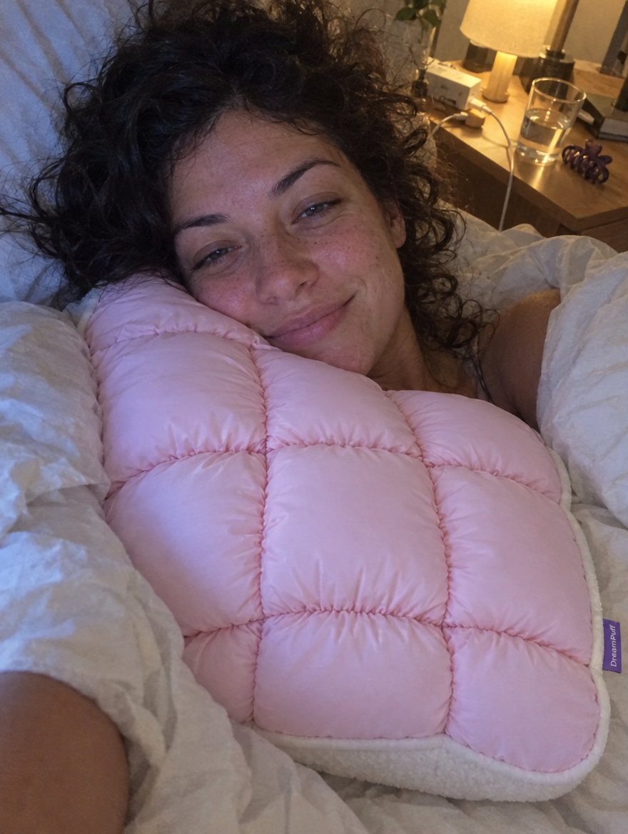Photo cliente : selfie au lit, la joue posée sur DreamPuff rose bébé