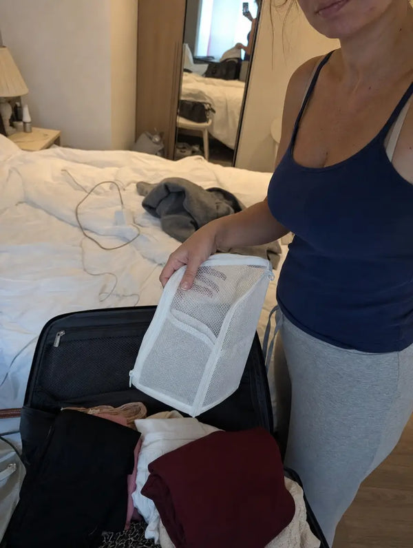 Voyageuse rangeant une TravelPouch pliee dans sa valise