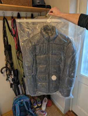 Photo client : doudoune grise adulte sous vide dans une housse SupremeStorage dans une entrée